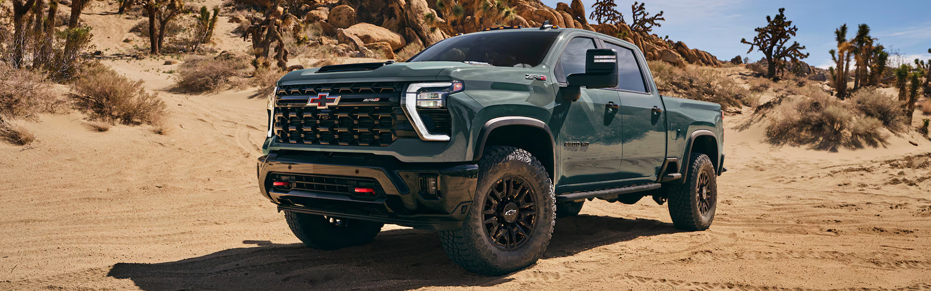 Green 2026 Chevrolet Silverado HD ZR2 off-road pickup parked in a desert landscape, highlighting its aggressive design and heavy-duty capability.